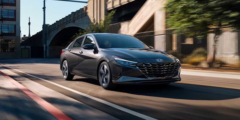 Gray Hyundai Elantra sedan driving through a city street.
