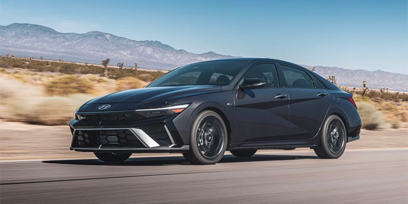 Hyundai Elantra sedan driving with mountains in the background.