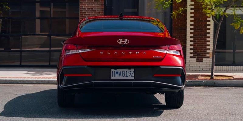 Red Hyundai Elantra Limited sedan rear view parked near a brick building.